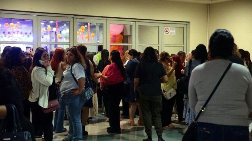 Crowd of People Gathered in a Hallway at an Event, Balloons Visible Through Glass Doors in the Background. - Justicia Regia