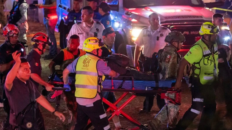 Ambulance Crew and Police Officers Move a Patient on a Wheeled Stretcher at Night, Surrounded by Responders and Emergency Vehicles. - Justicia Regia
