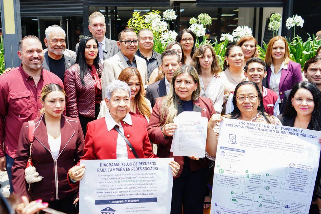 Group of Diverse Adults in Business Attire Posing Outdoors, Holding Large Posters with Spanish Text About Resources and Campaigns. - Justicia Regia