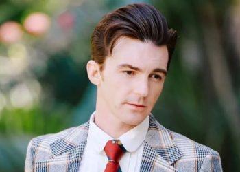 Portrait of a Man in a Plaid Blazer and Red Tie Looking Downward Outdoors in a Garden Setting. - Justicia Regia