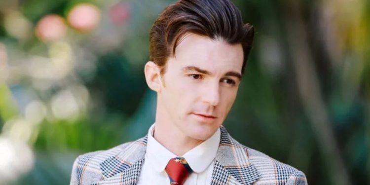 Portrait of a Man in a Plaid Blazer and Red Tie Looking Downward Outdoors in a Garden Setting. - Justicia Regia