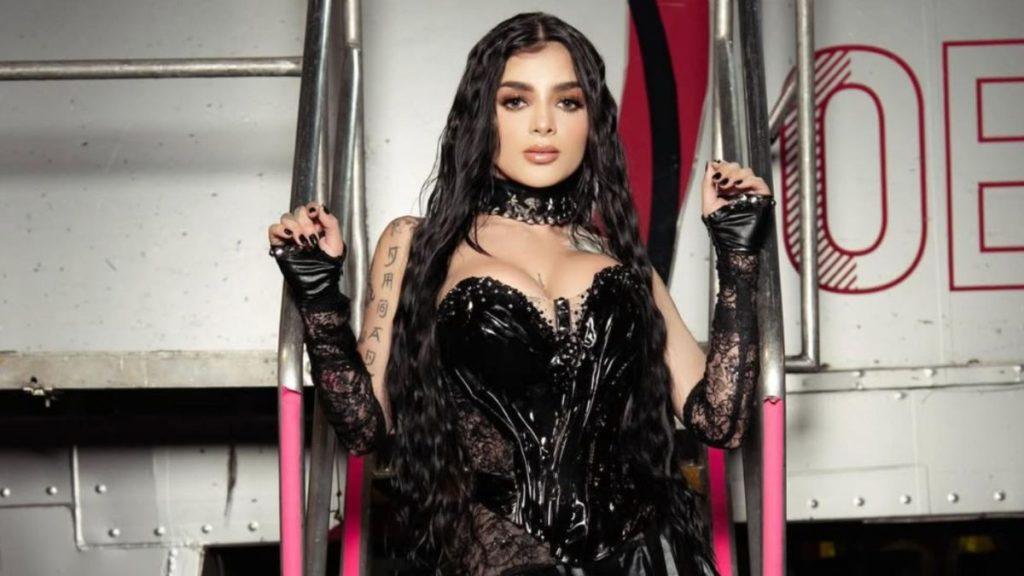 Bloque 2- Julio - 2026-07-30t163807302 - Justicia Regia Woman in a Glossy Black Latex Corset and Lace Gloves Posing Between Pink Metal Bars in an Industrial Setting, Long Dark Hair and Choker Visible. - Justicia Regia