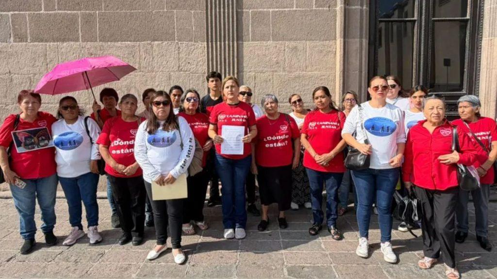 Coletivo-personas-desaparecidas-nuevo-leon - Justicia Regia Group of People in Red and White Shirts Stand Together Outside a Stone Building, Participating in a Demonstration. - Justicia Regia